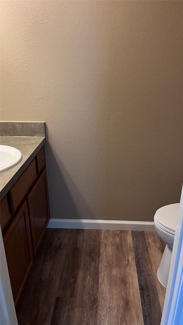 bathroom with wood-type flooring, vanity, and toilet