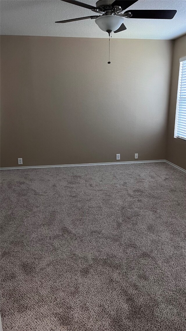 carpeted empty room with ceiling fan and a textured ceiling