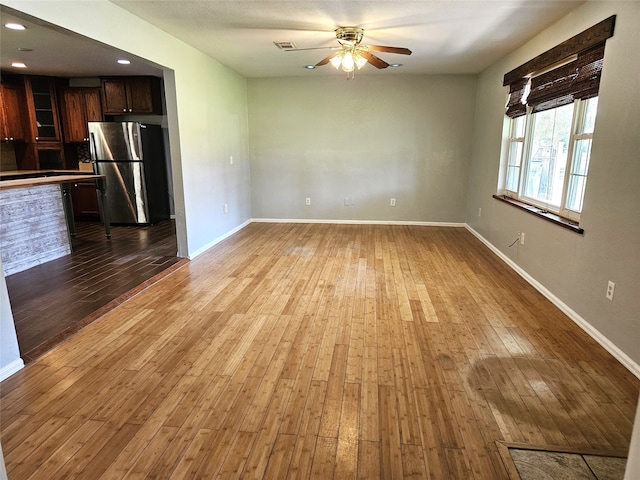 unfurnished living room featuring ceiling fan and light hardwood / wood-style flooring