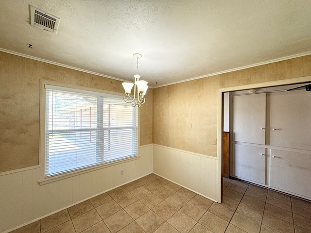 unfurnished dining area with tile patterned flooring, ornamental molding, a notable chandelier, and a textured ceiling