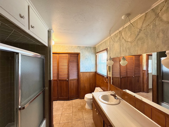 bathroom with vanity, a shower with door, tile patterned floors, wood walls, and toilet