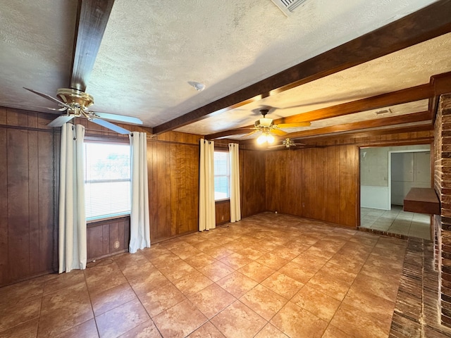 empty room featuring wooden walls, ceiling fan, and a textured ceiling