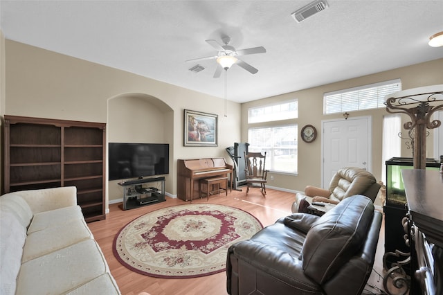 living room with a textured ceiling, ceiling fan, and light hardwood / wood-style flooring