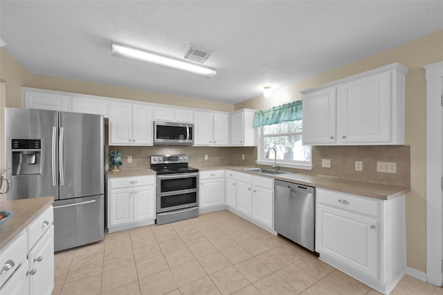 kitchen with appliances with stainless steel finishes, backsplash, sink, and white cabinets