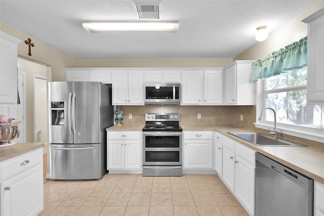 kitchen featuring light tile patterned floors, white cabinets, stainless steel appliances, and sink