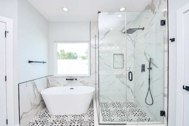 bathroom with tile patterned floors, tile walls, and separate shower and tub