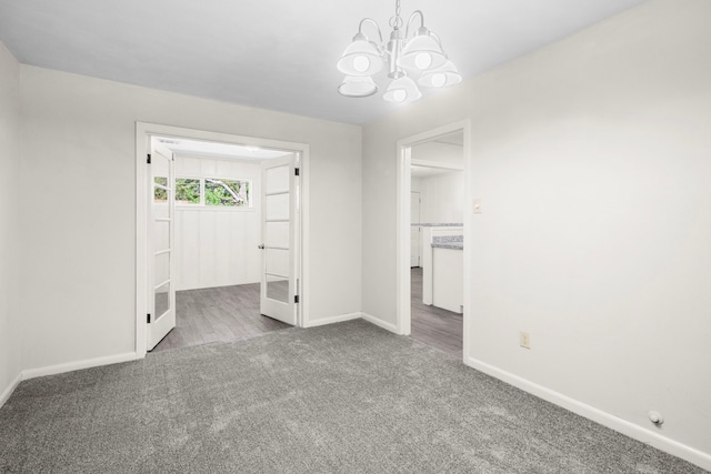 carpeted spare room featuring a chandelier