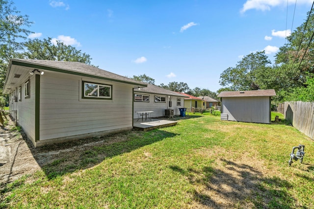 rear view of house with a lawn, central AC, a wooden deck, and a storage unit