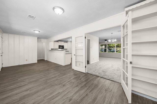 unfurnished living room with an inviting chandelier and dark hardwood / wood-style flooring