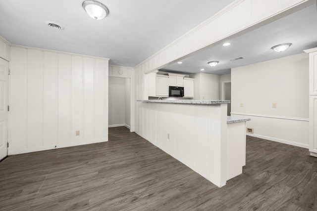 kitchen with kitchen peninsula, light stone counters, white cabinetry, and dark hardwood / wood-style flooring