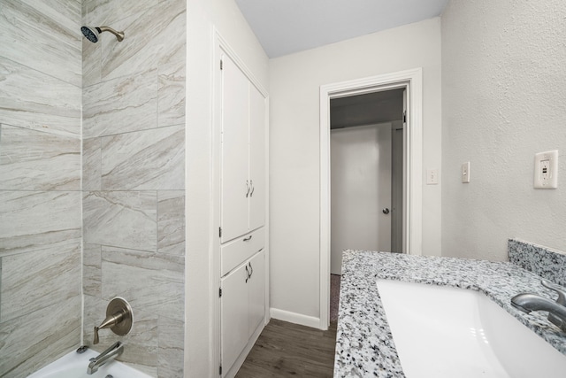 bathroom with wood-type flooring, tiled shower / bath, and vanity