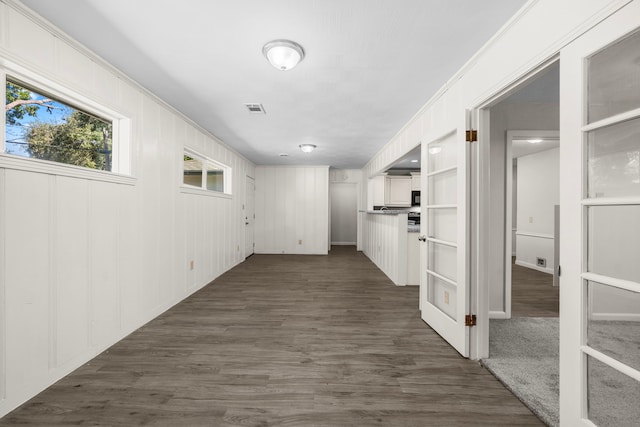 corridor featuring ornamental molding, dark wood-type flooring, and wood walls