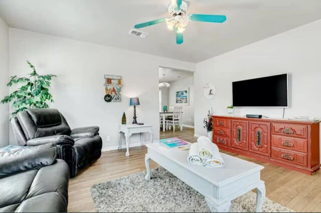 living room with ceiling fan with notable chandelier and light wood-type flooring