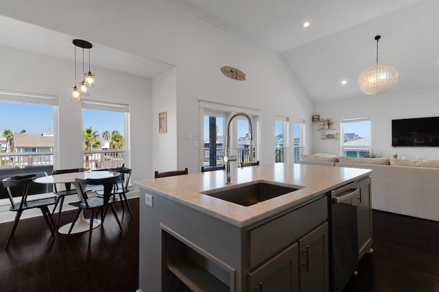 kitchen featuring pendant lighting, sink, a kitchen island with sink, vaulted ceiling, and dark hardwood / wood-style flooring