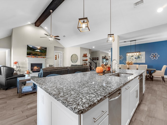 kitchen featuring white cabinetry, sink, lofted ceiling with beams, decorative light fixtures, and light wood-type flooring