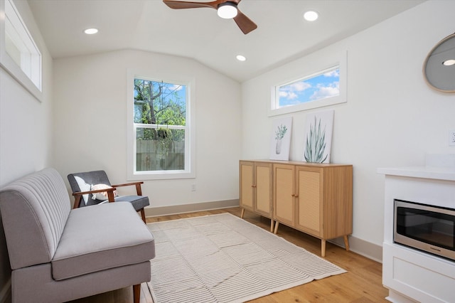 living area featuring ceiling fan, light wood-type flooring, and vaulted ceiling