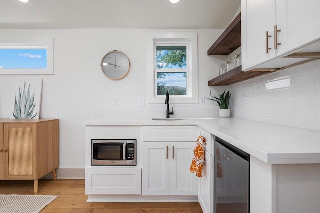 kitchen with sink, tasteful backsplash, light hardwood / wood-style floors, white cabinets, and appliances with stainless steel finishes