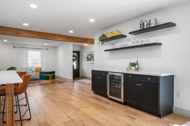 bar with beam ceiling, light wood-type flooring, and wine cooler