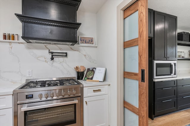 kitchen featuring tasteful backsplash, white cabinetry, stainless steel appliances, and light wood-type flooring