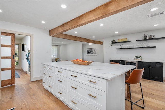 kitchen with light wood-type flooring, a kitchen breakfast bar, a center island, and white cabinets