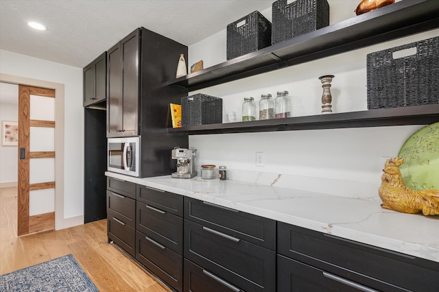 kitchen featuring light stone countertops, light hardwood / wood-style flooring, and a textured ceiling