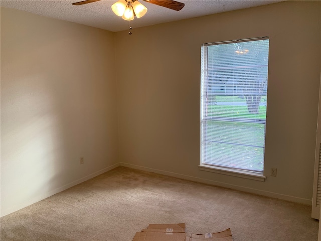 unfurnished room featuring ceiling fan, light colored carpet, and a textured ceiling