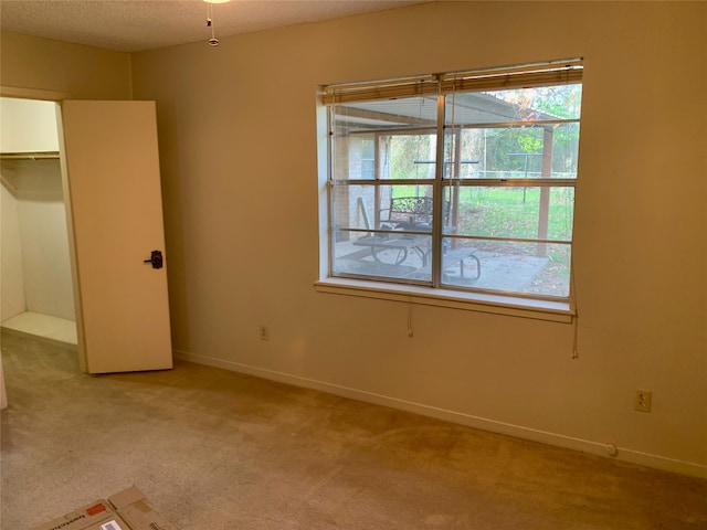 unfurnished bedroom with a closet, light colored carpet, and a textured ceiling