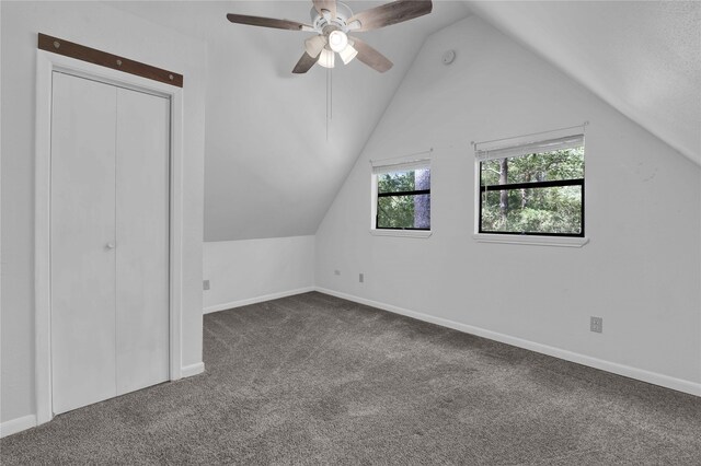 additional living space featuring ceiling fan, lofted ceiling, and dark colored carpet