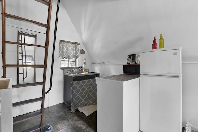 kitchen with white refrigerator, lofted ceiling, and sink