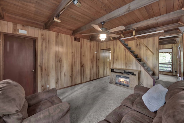 living room featuring wooden walls, light colored carpet, rail lighting, and beamed ceiling