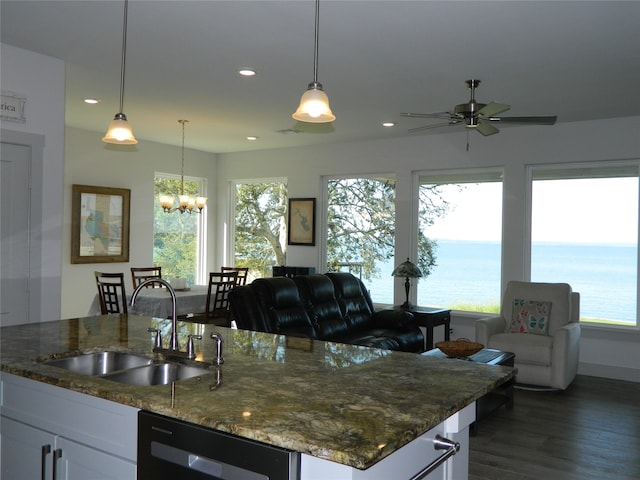 kitchen with white cabinets, dark stone counters, sink, and a water view