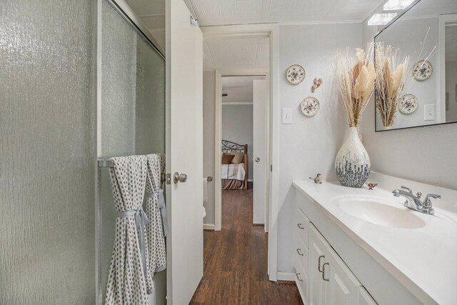 bathroom featuring vanity, hardwood / wood-style flooring, a shower with shower door, and crown molding