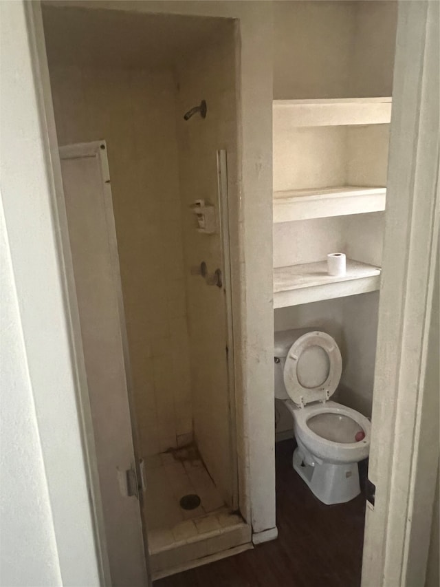 bathroom with hardwood / wood-style flooring, tiled shower, and toilet