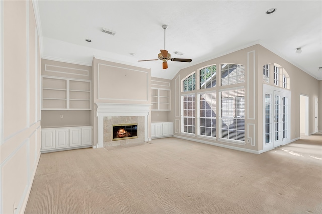 unfurnished living room featuring ceiling fan, lofted ceiling, built in shelves, and light colored carpet