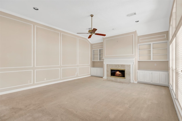 unfurnished living room with ceiling fan, light carpet, and built in shelves