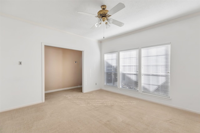 empty room with crown molding, light colored carpet, and ceiling fan