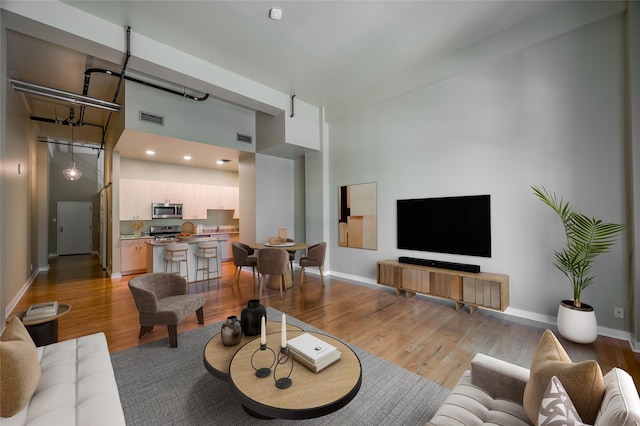 living room with light wood-type flooring and a towering ceiling