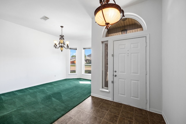 foyer with dark carpet and a notable chandelier