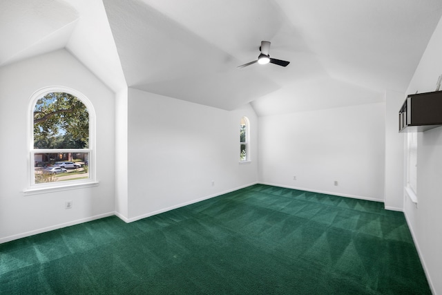 interior space featuring ceiling fan, vaulted ceiling, and dark carpet