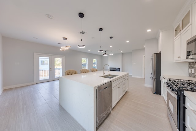 kitchen with pendant lighting, sink, a center island with sink, white cabinetry, and appliances with stainless steel finishes