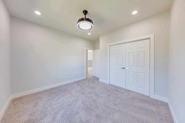 unfurnished bedroom with light carpet and a closet