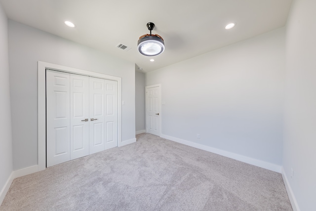 unfurnished bedroom with ceiling fan, light colored carpet, and a closet