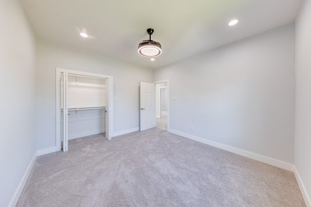 unfurnished bedroom with a closet and light colored carpet