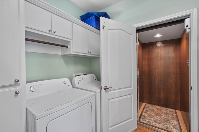 laundry area featuring washing machine and dryer, hardwood / wood-style floors, and cabinets