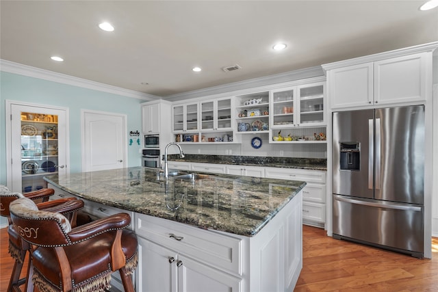 kitchen with a kitchen island with sink, stainless steel appliances, white cabinets, sink, and light hardwood / wood-style flooring