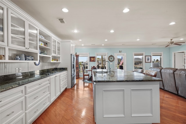 kitchen with dark stone countertops, sink, light hardwood / wood-style floors, and stainless steel refrigerator with ice dispenser