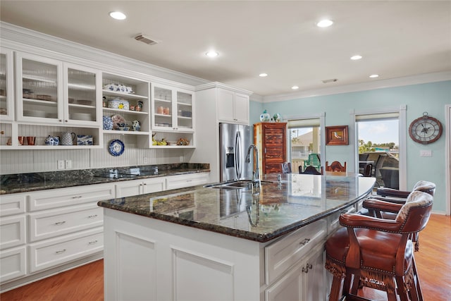 kitchen featuring stainless steel fridge, sink, a center island with sink, light wood-type flooring, and crown molding