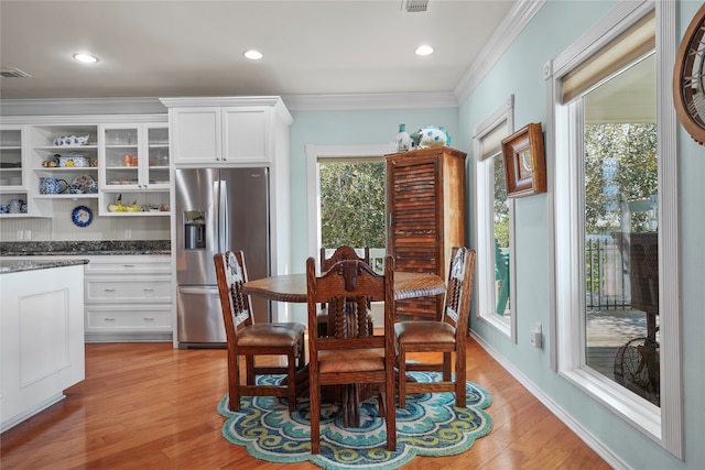 dining space featuring light hardwood / wood-style flooring, crown molding, and a wealth of natural light