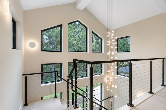 stairs featuring lofted ceiling with beams and a chandelier