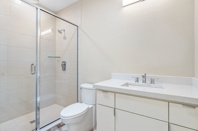 bathroom with vanity, a shower with shower door, and toilet